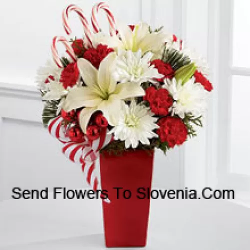 Bursts with the bright cheer and jubilant beauty of this special season. White Asiatic Lilies and chrysanthemums sit amongst red mini carnations, assorted holiday greens, red glass balls, three candy canes and festive ribbon, perfectly arranged in a red ceramic vase to create a lively bouquet of merry wishes for a splendid holiday season! (Please Note That We Reserve The Right To Substitute Any Product With A Suitable Product Of Equal Value In Case Of Non-Availability Of A Certain Product)